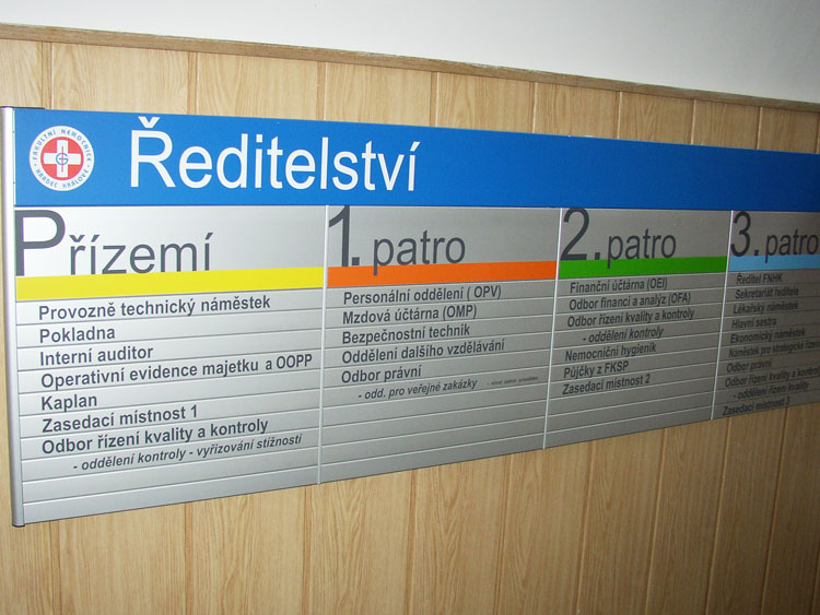 Informační cedule. Cedule vyobrazuje informace s rozdělením budovy. Tabule zobrazuje oddělení pro jednotlivá patra budovy Ředitelství.